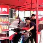 Marlboro promotional booth with red branding setup and people interacting at an outdoor marketing event.